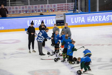 Apulaispormestari jakaa palkinnot koululaisille jääkiekkoilijoille kentällä.