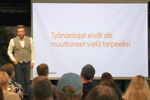 Pasi Rautio esiintyy diaesityksensä edessä.