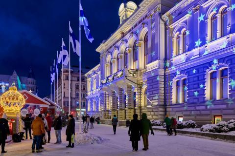 People at the Old City Hall. Finnish flags in flagpoles.