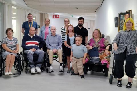 Tampereen vammaisneuvoston jäseniä ryhmäkuvassa. Etualalla olevista moni istuu pyörätuolissa. Kaikki näyttävät hyväntuulisilta.