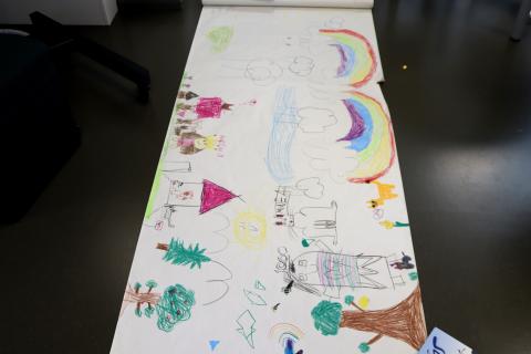 Lapset ovat piirtäneet värikkäitä kuvia isolle valkoiselle paperille.