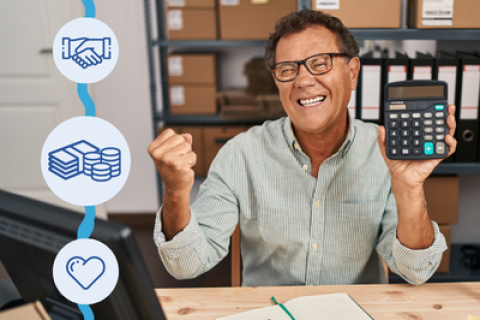 Työnantaja istuu työpöydän ääressä ja pitelee laskinta. Hän hymyilee ja hänen toinen kätensä on nyrkissä ilmassa.