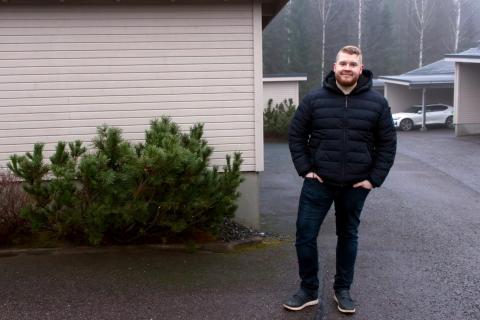 Taloyhtiön puheenjohtaja seisoo pihassa hämäränä päivänä.