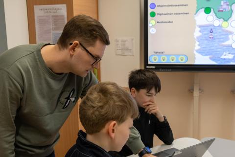 Aleksi Huttu guides two students at the table.