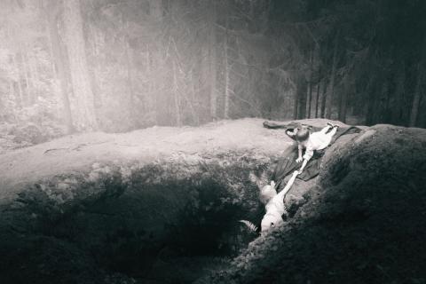 A child hold out a hand to help another out of a giant's kettle aka hiidenkirnu.