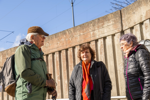 Three seniors are standing outside in their winter coats, chatting.