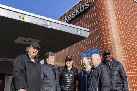 Ali Leppälahti, Seppo Asp, Erkki Räsänen, Kimmo Leinonen, Harri Kanto and Ronald Fraser are gathered in front of Tampere Swimming Centre on a sunny spring day.