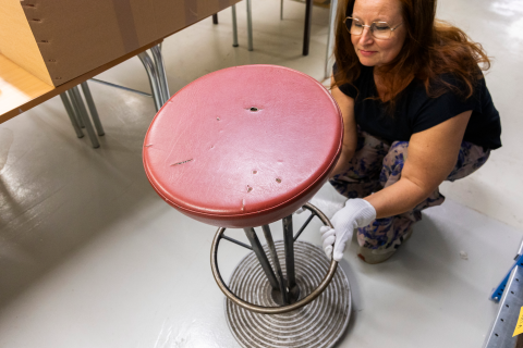 A specialist at the Finnish Labour Museum Werstas is crouched down looking at a bar stool.