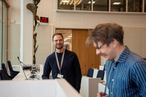 Mikael is standing in the background, looking at Henrik, who is sideways in the picture, smiling broadly with his eyes almost closed.