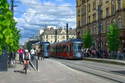 Hämeenkatu Keskustorin kohdilta, joissa kaksi ratikkaa ajaa toisiaan vastaan pyöräilijöiden ja kävelijöiden liikkuessa vierellä.