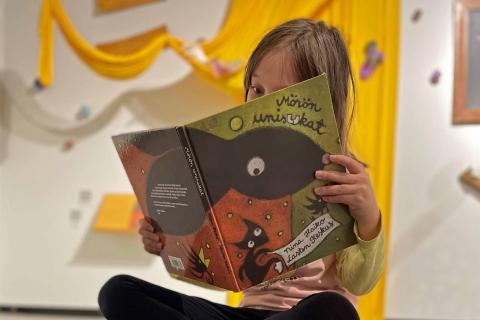 Lapsi lukee lattialla kirjaa.