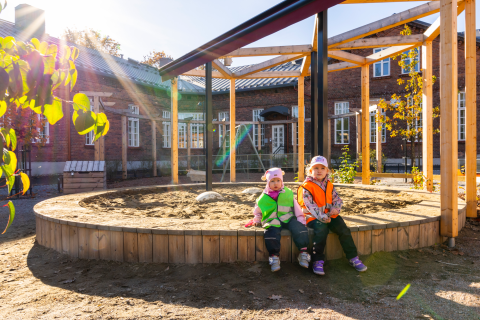 Kaksi päiväkodin lasta istuu Ruusupuiston päiväkodin pihalla.