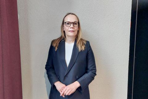 Tummansiniseen jakkuun pukeutunut Päivi katsoo suoraan kameraan.