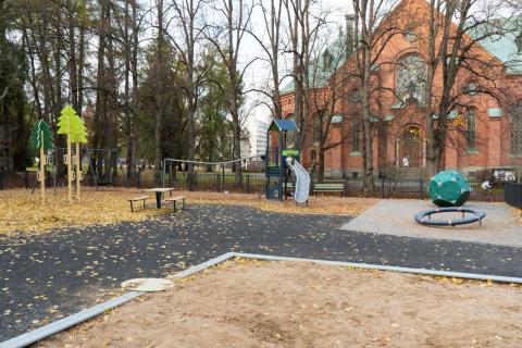 Pyynikin kirkkopuiston leikkipaikan telineitä ja kirkko taustalla syksyllä.